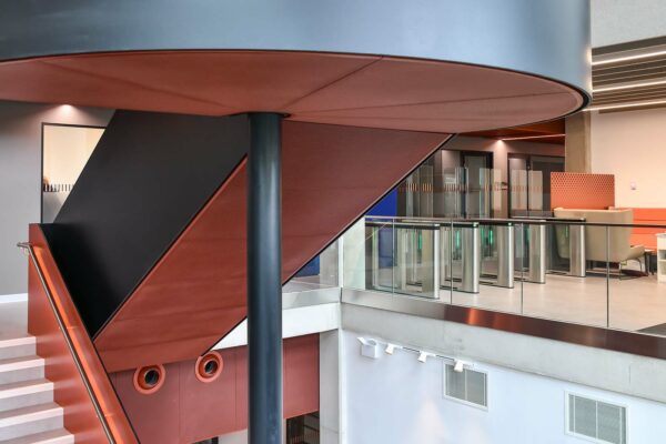 OWA UK's bespoke, metal, perforated, staircase panels with class A acoustic pads. Curved segments under the half landing.